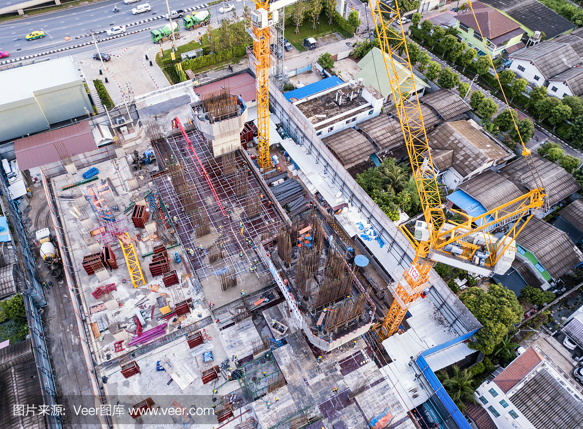 繁忙的工業(yè)建筑工地工人與起重機(jī)一起工作的鳥瞰圖。中午發(fā)展高層建筑大樓俯視圖。